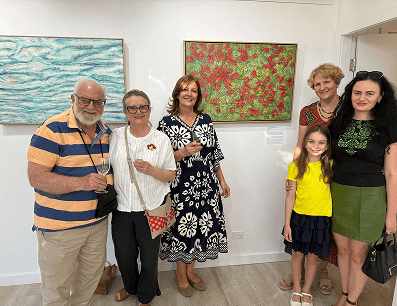 Award-winning artist with guests in front of her artwork that is available to purchase online