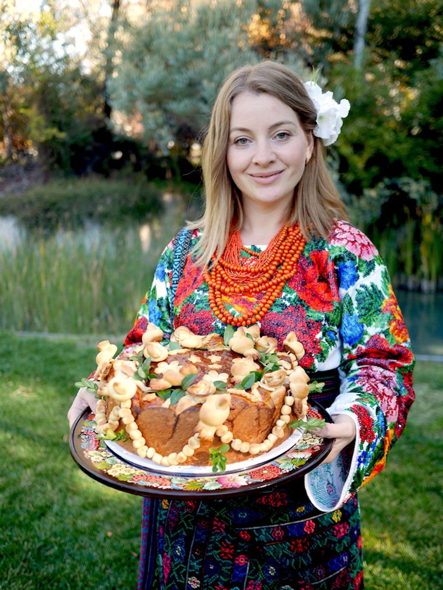 A model holding korovaj on the grass in front of NGA