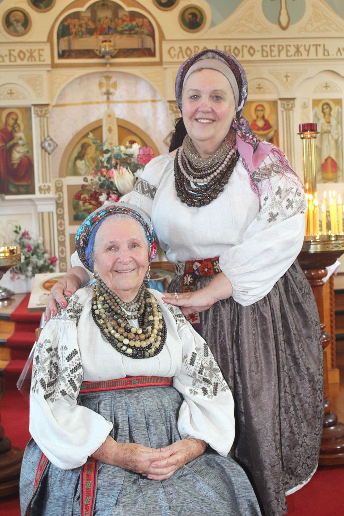 Mother and daughter in traditional Ukrainian costumes in the church