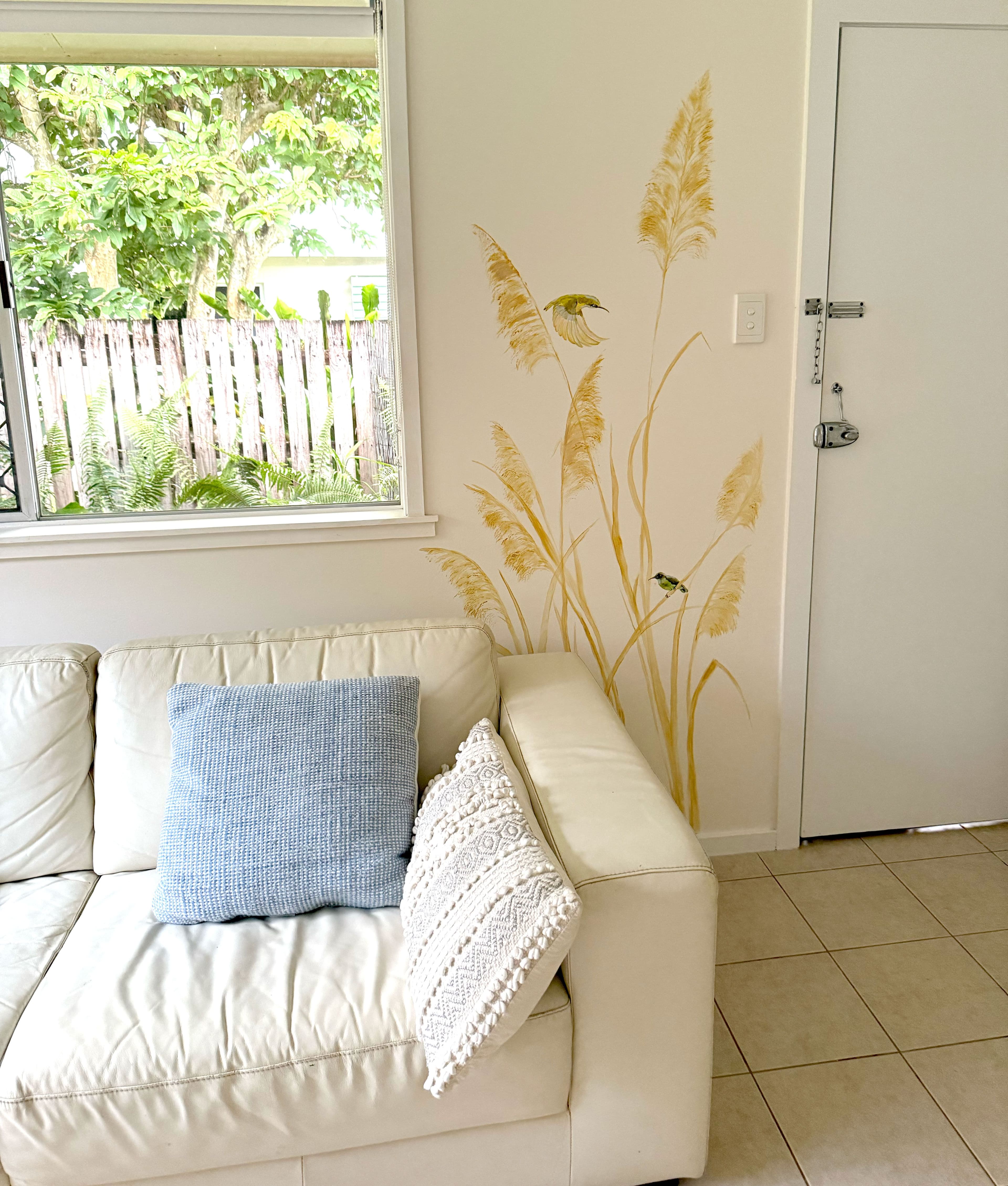 Light living room decorated with mural of sandy colour tall grasses and birds