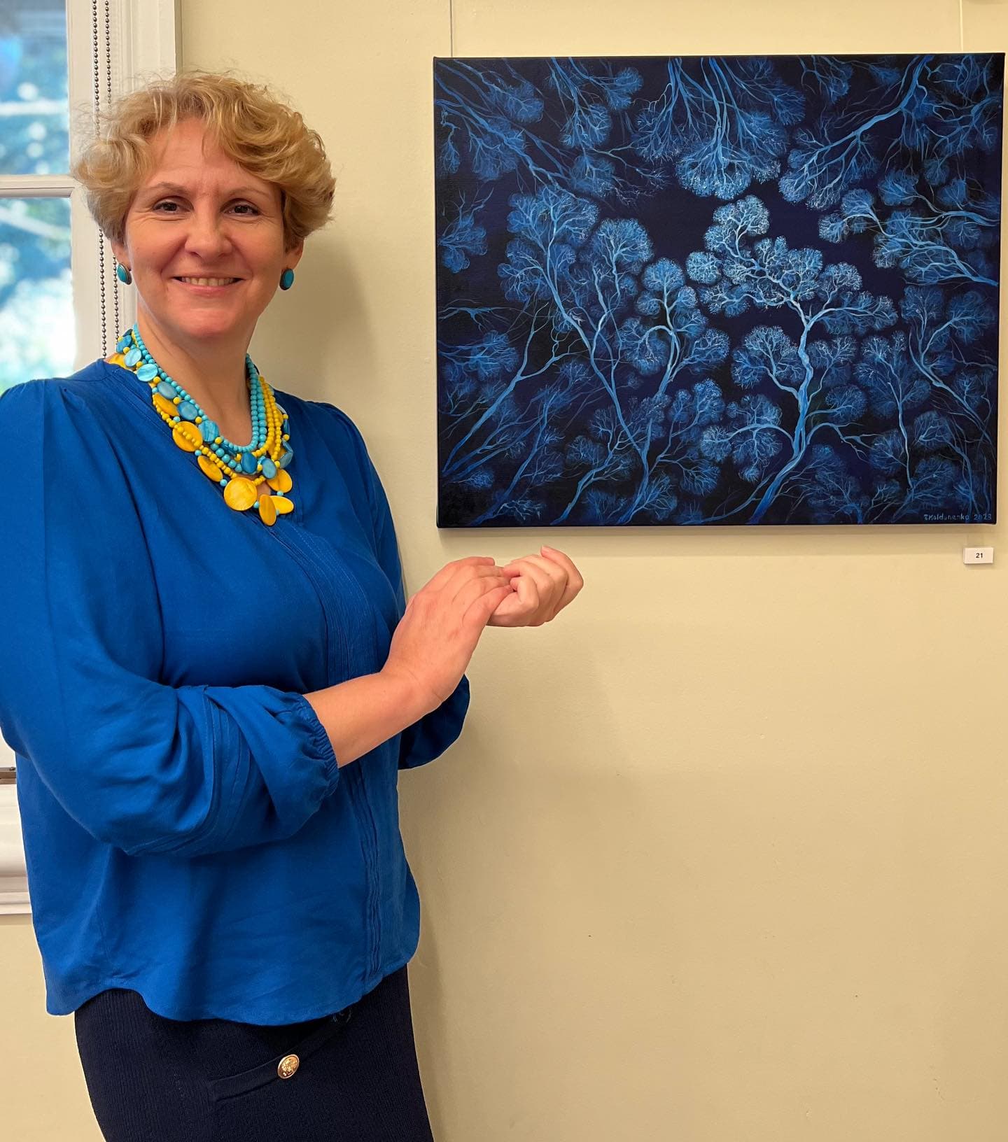 Tetiana Koldunenko in front her artwork