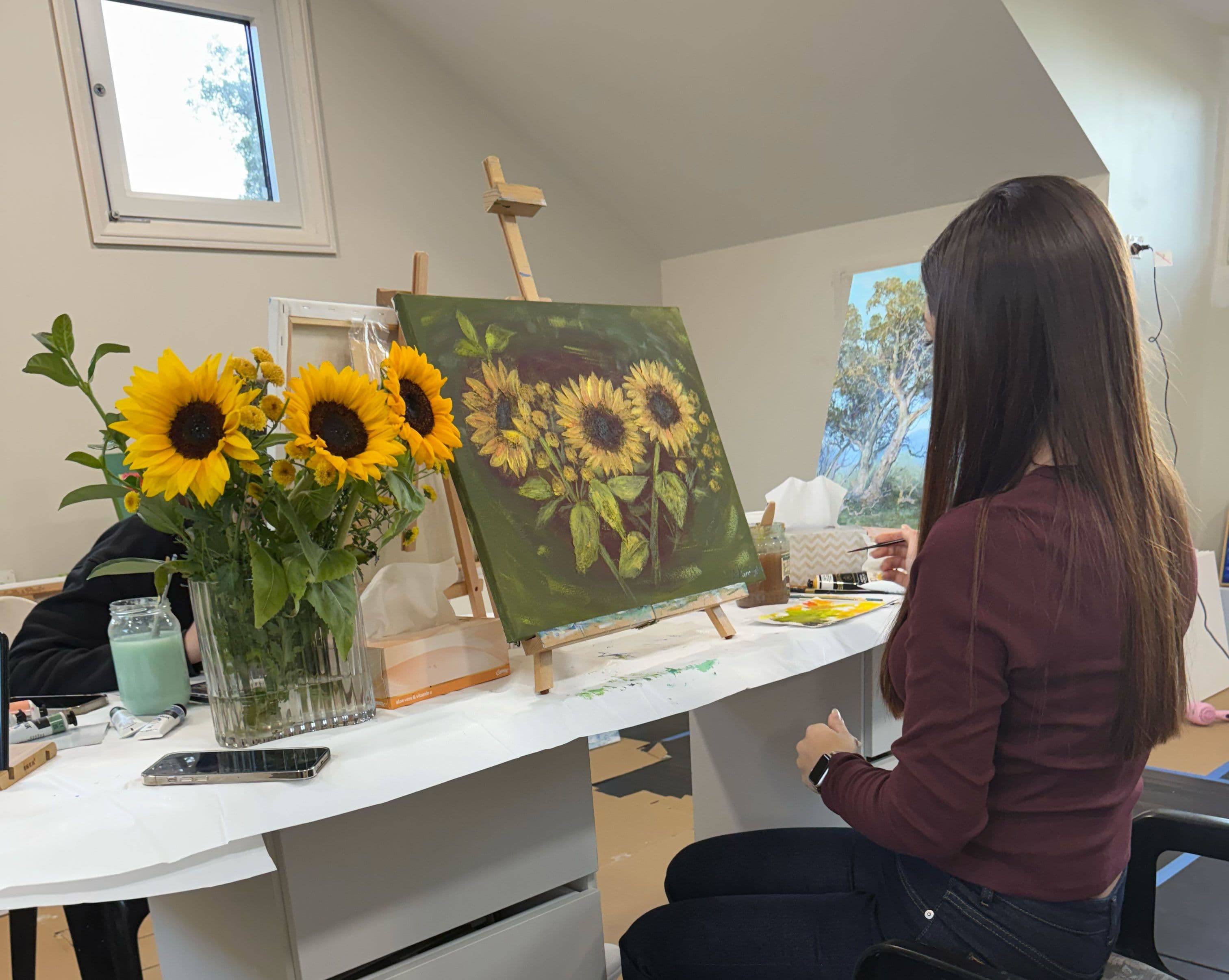 A girl in the artists studio painting sunflowers